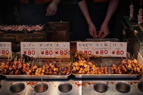 在你等待的时候 一个日本的日本黑社会站着烤着肉 每根80元 他们在最后数着 你付了钱 — 图库照片