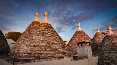 Güneş, İtalya 'nın Puglia bölgesindeki Alberobello kentindeki Trulli Evi çatılarından doğuyor..