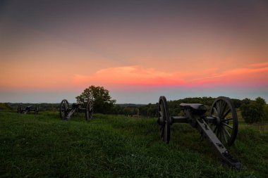 Akşam güneşi, Amerikan İç Savaş toplarından oluşan bir üçlüye batıyor..