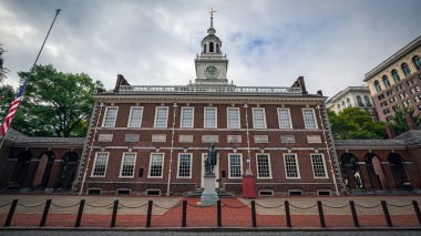 Philadelphia 'daki Bağımsızlık Salonu' nun önünde bulutlu bir yaz gününde Amerikan bayrağı yarıya inmiş..