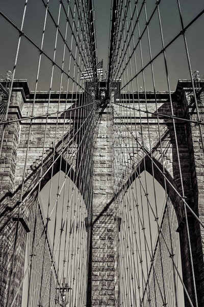 Look up at the suspension cables and arches of a New York City bridge.