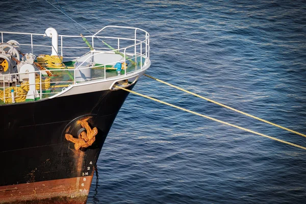 The rope, chains, and anchor on the bow of a ship tied to a dock in Yokosuka, Japan.