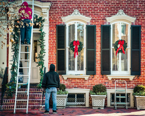 Рабочие вешают рождественские венки на колониальный дом в северной Вирджинии
.