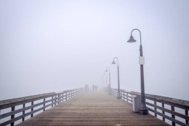 Imperial Beach rıhtımındaki sisin içindeki insan siluetleri..