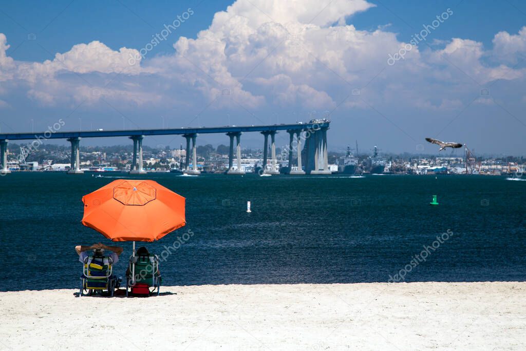 Tourists relaxing on a beach at Glorietta Bay in Coronado, CA.