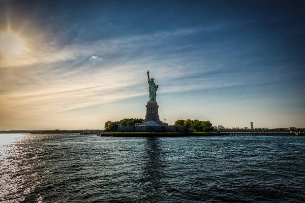 The Statue of Liberty in New York with the setting sun behind her.