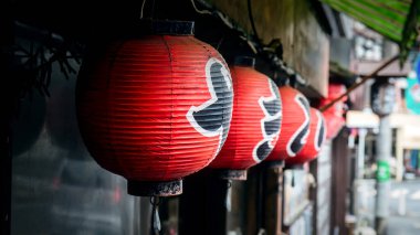 Kırmızı fenerler bir Japon restoranının önündeki kaldırımda asılı..