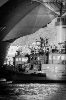 Üç römorkör bir Japon Deniz Savunma Gücü gemisini iskelesine doğru yönlendiriyor..