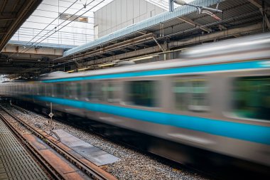 Yerel bir tren istasyonundaki bir platformdan hızla geçen bir tren..