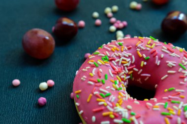 Siyah arka planda donut, üzüm ve renkli toplar.