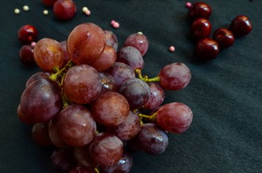 Üzümler, renkli toplar ve siyah arka planda kirazlar