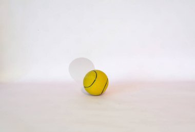 Çizgili sarı tenis topu ve beyaz arka planda gölge.