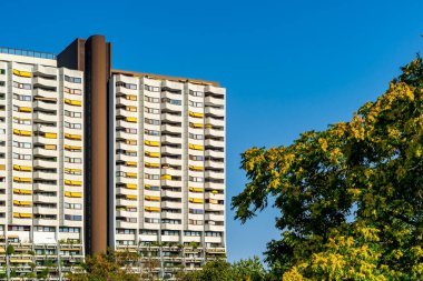 Balkonlarında yeşil bitkiler ve sarı tenteler olan beyaz binalar.
