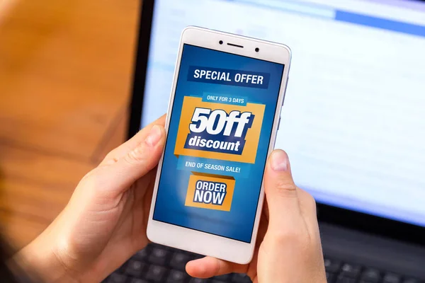 % 50 indirimli. Ekranda% 50 indirim reklamı olan akıllı telefon tutan bir kız. Pazarlama, ecommerce, cep telefonu tanıtımı. Sınırlı bir süre. Şimdi Al.