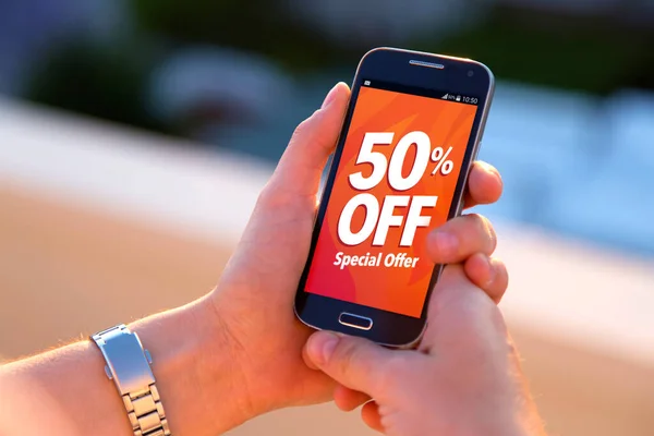 % 50 indirimli. Ekranda% 50 indirim reklamı olan akıllı telefon tutan bir kız. Pazarlama, ekommerce, cep telefonu tanıtımı.