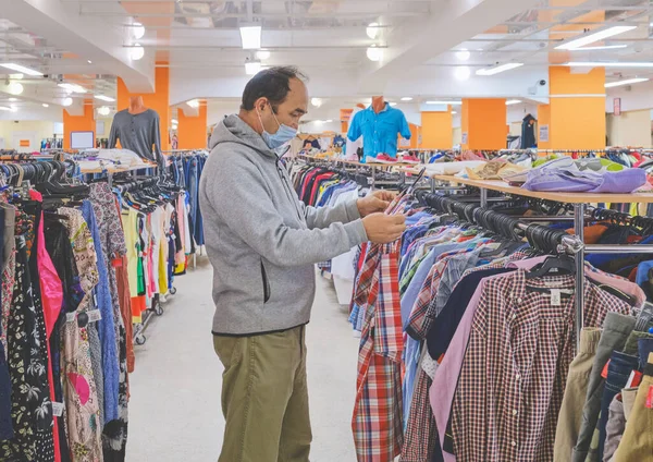 Mature Man Mask Choosing Clothes Second Hand Store Conscious Consumption — Stock Photo, Image