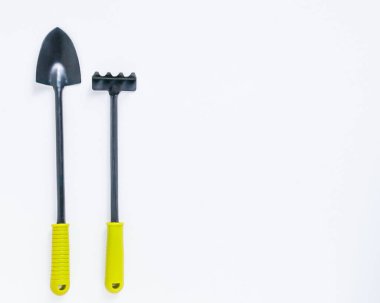 Beyaz arka planda küçük siyah bir kürek ve tırmık. metin üstü görünüm tarım kavramı için yer