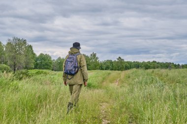 Sivrisinek kostümlü, sırt çantalı, çayırda yürüyüş yapan aktif bir adam. Sibirya, Rusya. Tek başına seyahat, yaşam tarzı, yerli turizm
