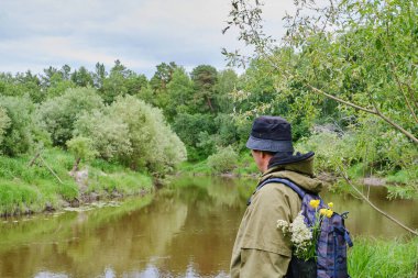 Sibirya 'daki bir ormanda sırt çantasıyla Tayga nehrinin yanında yürüyüş yapan sivrisinek kostümlü aktif bir adam. Tek başına seyahat, yaşam tarzı, yerli turizm