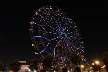 Sochi, Adler, Rusya - 3 Mart 2020: Olimpik Park 'ın yanındaki Imereti ovalarında eğlence temalı Park' ta dönme dolabın aydınlatılması. Çekim Çarkıfeleği