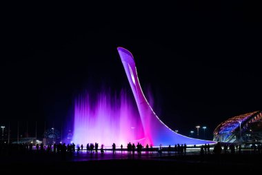 Sochi, Rusya - 3 Mart 2020 Olimpik Park Sochi 'de akşam gösterisi. Mitolojik bir ateş kuşunun heykeli. Olimpiyat ateş topu çeşmesi