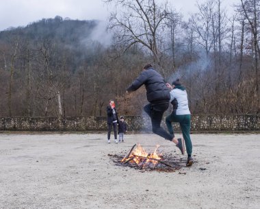 Sochi, Rusya - 1 Mart 2020 Gözleme Haftası Korkuluğu Yanan Ayin Geleneksel Slav mitolojisi elementleri içeren Eşofmanlı genç çift Ateş Bulanıklığı 'nın üzerinden atlıyor