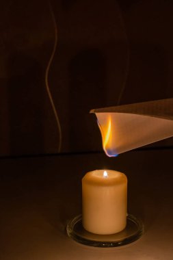 Mum ve kağıt üzerinde antik fal bakımı. Siyah bir arka planda, yanan bir mumun alevinden beyaz bir kağıt yanıp sönüyor. Kehanet yıkım konsepti.