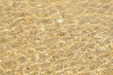 Baykal Gölü 'nde, kum ve küçük taşlar berrak su ve güneşli parlaklıkla görülebilir. Hareket bulanıklığı. Doku