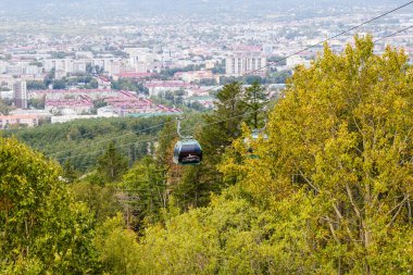 Yuzhno-Sakhalinsk, Rusya - 30 Ağustos 2019. Kablolarda, şehrin ve ormanın arka planına karşı. Turist kompleksi Gorny Vozdukh