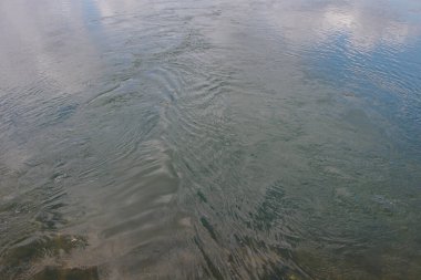 Arka plan olarak su akışı dokusu. Mavi gökyüzü ve bulutlardan oluşan nehirde yansıma.