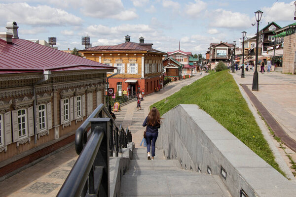 Irkutsk, Russia - August 12, 2019: people walk around a tourist place - the 130th Quarter. In the foreground, a girl goes down the stairs
