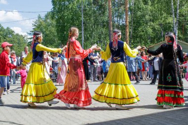 Yekaterinburg, Rusya, 15 Haziran 2019. İnsanlar el ele tutuşup daireler çizerek dans ediyorlar. Yıllık Tatarlar ve Bashkirs Sabantuy bayramı şehir parkında.