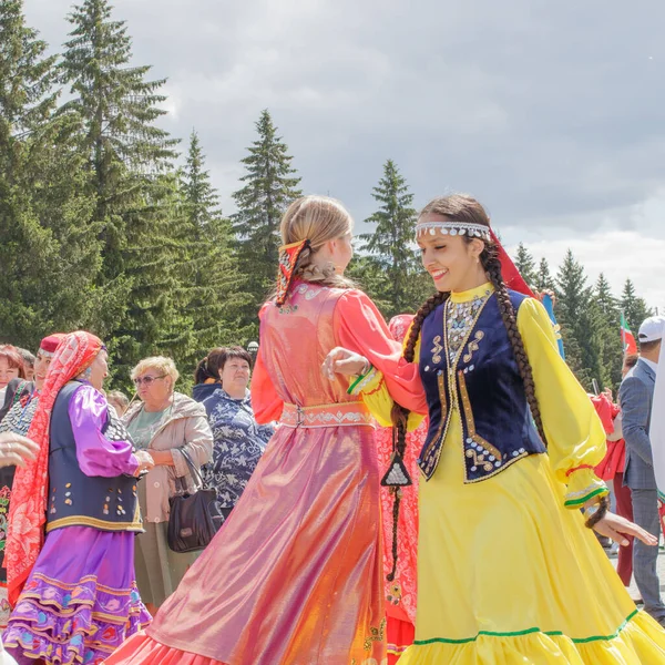Yekaterinburg, Rusya, 15 Haziran 2019. Ulusal kıyafetli iki kız ön planda dans ediyor. Yıllık Tatarlar ve Bashkirs Sabantuy bayramı şehir parkında.