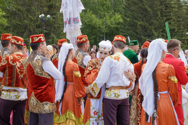 Yekaterinburg, Russia, June 15, 2019. A girl and a guy in Tatar national clothes hugging among a crowd of people. The annual national holiday of the Tatars and Bashkirs Sabantuy in the city park.