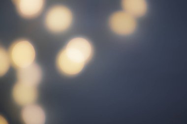 Solunda tek renkli büyük ışıklar olan koyu bulanık bir arkaplan. Odaklanmayın