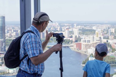 Bir çocuk ve büyükbabası, Rusya 'nın Yekaterinburg kentindeki bir binanın panoramik penceresinde dikiliyorlar.