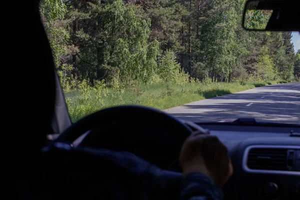 Widok Leśnej Drogi Przedniego Okna Samochodu Ręka Kierowcy Trzymająca Kierownicę — Zdjęcie stockowe