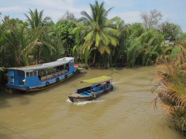 Ben Tre, Vietnam, 3 Ocak 2015. Mekong Nehri 'nin dar deltasında yürüyüş için büyük bir tekne turistleri bekliyor. Dümeni olan küçük ahşap bir tekne yüzer
