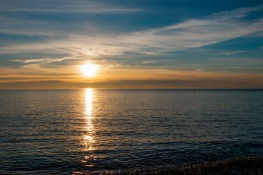 Deniz kıyısında güzel ve parlak gün batımı mavi ve sarı tonlarda. Sahilden görünüm.