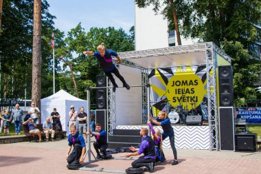 Jurmala, Letonya - 15 Temmuz 2018: Jomas Caddesi 'nin geleneksel yaz festivalinde bir grup jimnastikçinin performansı. Bilet yok. Genç bir adam direkten atlıyor.