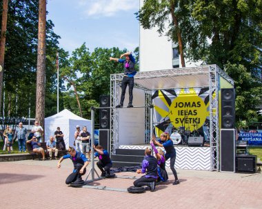 Jurmala, Letonya - 15 Temmuz 2018: Jomas Caddesi 'nin geleneksel yaz festivalinde bir grup jimnastikçinin performansı. Bilet yok. Genç bir adam dengesini direğin üzerinde tutar.