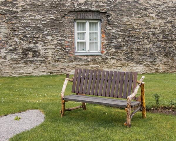 Unusual rural wood bench made of boards and branches against the background of the stone wall of the old city in Tallinn, Estonia.