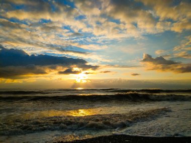 Karadeniz kıyısında mistik gün batımı. Parlak renkler, büyük dalgalar. Kış mevsimi.