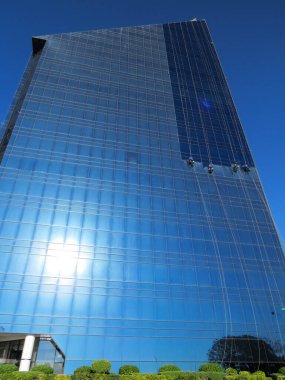 Endüstriyel tırmanışçılar yüksek katlı bir ofis binasının cam cephesini yıkıyorlar..