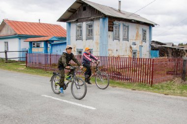 Aromashevsky Rusya 27 Mayıs 2018 İki genç bisikletle eski evin önünden geçiyor