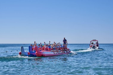 Sudak - 11 Eylül 2020: Yaz deniz manzarası. Can yelekli bir grup turist teknenin arkasındaki büyük bir katamarana biniyor..
