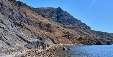 Sudak - 12 Eylül 2020: Turistler Karadeniz kıyısındaki Cape Meganom 'un kayalık kıyıları boyunca yürüyorlar. Pankart