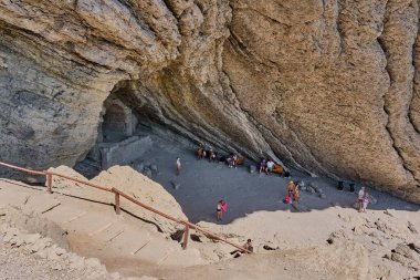 Sudak, Ukrayna - 14 Eylül 2020: Karadeniz kıyısı. İnsanlar Koba-Kaya dağından dalgalarla oyulmuş bir mağarada dinleniyorlar. Manzaralı doğal bir eğlence, Golitsyn mağarası.
