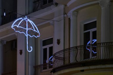 Pencereye yansıyan, parlak bir şemsiye şeklinde akşam sokak ışıkları.