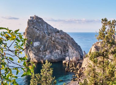 Kıyı deniz manzarası. Rock Diva, Yalta yakınlarındaki Karadeniz kıyısında. İnsanlar asma köprüde yürüyor, tepeye tırmanıyor, sahilde dinleniyor.